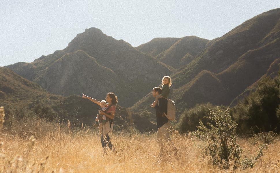 family of four walking across a field with mountains in the background