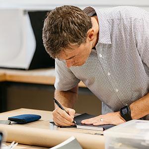 a man writing on a piece of paper.