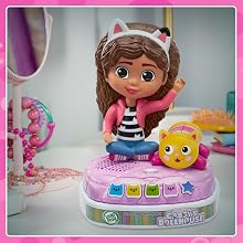 Kid presses story button while the rainbow lights on Gabby’s base glow. Notes show music.