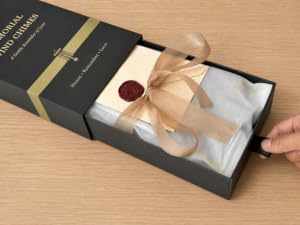 Closed black memorial wind chime gift box on a light wood table.