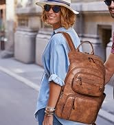 Black multi-compartment laptop backpack shown on a model wearing white t-shirt, photographed against architectural stone columns background.