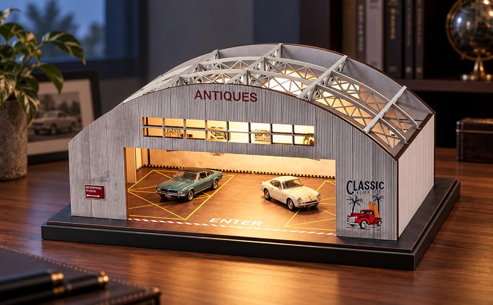 Vintage hangar diorama with warm lighting and two model cars on a wooden desk