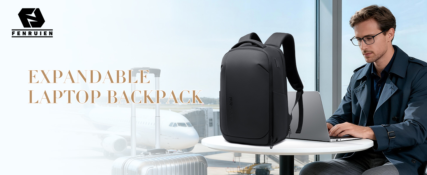 A man works on a laptop beside a black FENRUIEN expandable backpack at an airport.