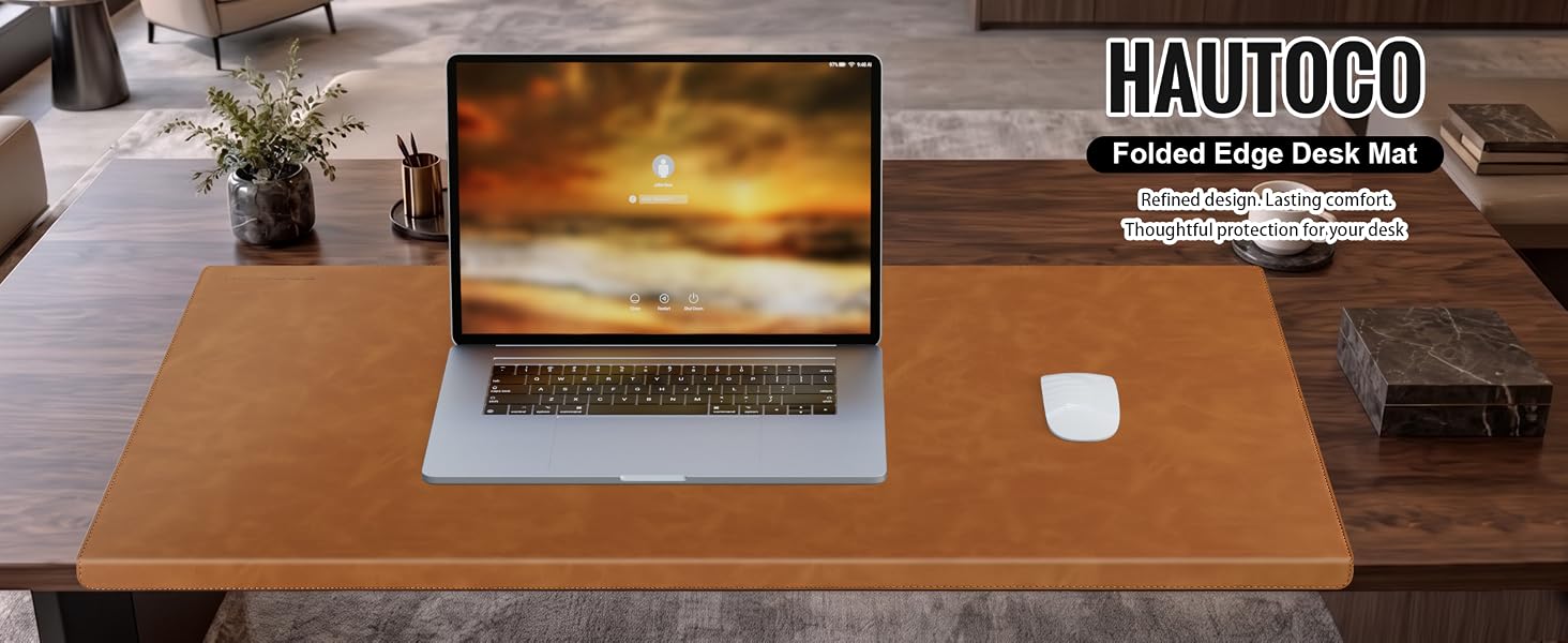 Text reads 'HAUTOCO' and 'Fashion Large Desk Pad'. Workspace setup showing wooden desk with laptop displaying sunset image, wireless mouse, and potted plant.